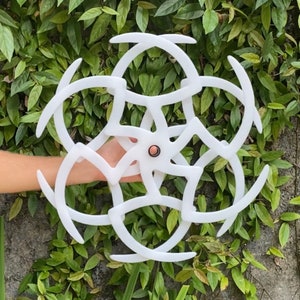 May include: White geometric mobile with a circular design and multiple curved arms. The mobile is made of plastic and has a white finish.