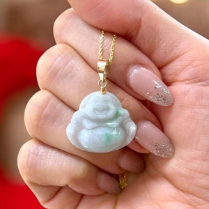 May include: A jade pendant in the shape of a laughing Buddha. The pendant is light green with a gold chain.