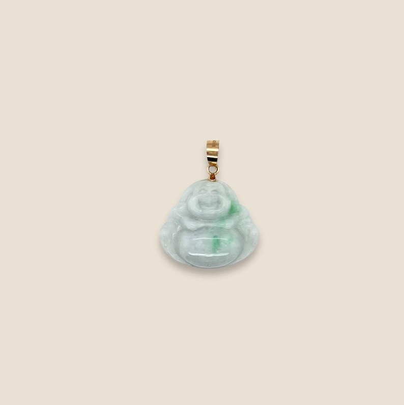 May include: A jade green and white laughing Buddha pendant with a gold bail.