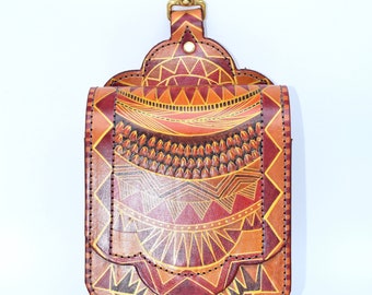 Puede incluir: Una bolsa de cuero marrón con un patrón geométrico en tonos naranja, amarillo y marrón. La bolsa tiene un gancho de latón en la parte superior y está decorada con costuras alrededor de los bordes.