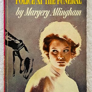 Puede incluir: Portada de libro de bolsillo vintage de "Police at the Funeral" de Margery Allingham. La portada presenta a una mujer con expresión preocupada, una mano sombreada y texto, incluido el título y el nombre del autor. El libro es de la serie Macfadden MB Books.