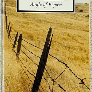 Puede incluir: Portada del libro "Angle of Repose" de Wallace Stegner. La portada presenta un paisaje con una valla de madera desgastada y alambre de púas contra un campo de hierba seca y dorada. El título y el autor están en un recuadro negro.