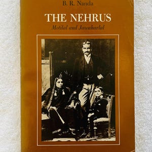 May include: A vintage book titled "The Nehrus" by B.R. Nanda. The cover is a warm brown with a sepia-toned family portrait. The book's title and author's name are in white text. The book is a historical biography.