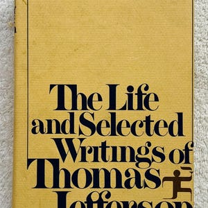 May include: A vintage book titled "The Life and Selected Writings of Thomas Jefferson" from the Modern Library series. The cover is a mustard yellow with black text. The book is edited by Adrienne Koch and William Peden.