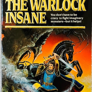 May include: A paperback book titled The Warlock Insane by Christopher Stasheff. The cover features a figure in a blue tunic and dark cape wielding a sword while standing before a black horse. A swirling white mist surrounds the figure against a sunset.