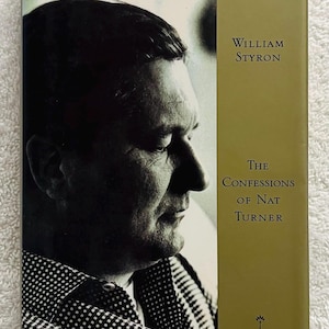May include: A vintage book cover featuring a black and white portrait of a man on the left side. The right side has text that reads "William Styron" and "The Confessions of Nat Turner" in a serif font, with a gold background.