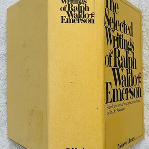 May include: A mustard-yellow hardback book with the title "The Selected Writings of Ralph Waldo Emerson" in black lettering. The book is part of the Modern Library series and includes a biographical introduction.