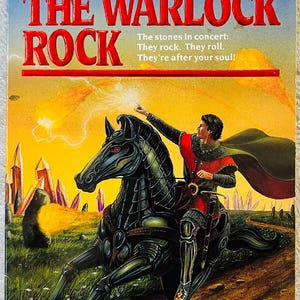 May include: A paperback book cover titled The Warlock Rock by Christopher Stasheff. The illustration depicts a person in medieval armor riding a black horse with red eyes, pointing toward glowing orange meteors in a yellow sky above purple crystals.