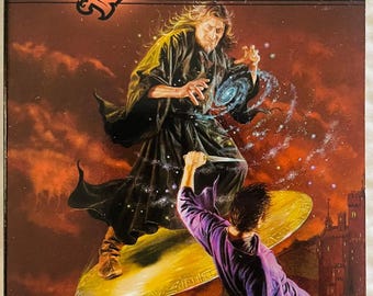 May include: A paperback book titled The Summoning: Return of the Archwizards Book 1 by Troy Denning. The cover art depicts a robed figure standing on a golden disc, casting a swirling blue galaxy spell, while another figure in purple reaches up.