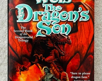 Könnte beinhalten: Ein Taschenbuch mit dem Titel "The Dragon's Son" von Margaret Weis. Das Cover zeigt einen roten Drachen, einen Krieger und einen feurigen Hintergrund. Der Text enthält "The Second Book of the Dragonvarld Trilogy" und ein Zitat von Publishers Weekly.