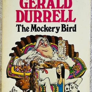 Può includere: Copertina di un libro tascabile vintage per "The Mockery Bird" di Gerald Durrell. L'illustrazione mostra un uomo con lunghi capelli bianchi, circondato da cani e una donna. Il titolo e il nome dell'autore sono in grandi lettere rosa.
