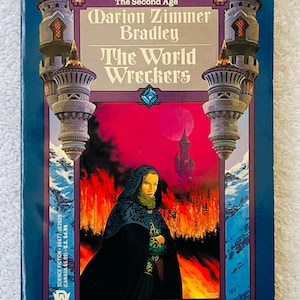 May include: A vintage paperback book, "The World Wreckers" by Marion Zimmer Bradley. The cover depicts a woman in a hooded cloak against a fiery backdrop and a castle. Part of the Darkover series, with text including "Against The Terrans".