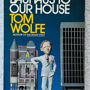以下が含まれることがあります： トム・ウルフ著「フロム・バウハウス・トゥ・アワー・ハウス」の表紙。白いスーツを着た男性がミニチュアの家と高層ビルに寄りかかっている漫画のイラストが特徴です。タイトルと著者の名前が大きく表示されています。
