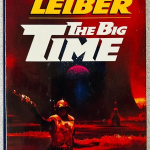 May include: Book cover for "The Big Time" by Fritz Leiber. The title is in white and yellow, with a futuristic illustration of a figure holding a weapon. The background is a deep red with a planet and a cityscape.