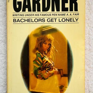 May include: Vintage paperback book titled "Bachelors Get Lonely" by Erle Stanley Gardner. The cover features a woman in a colorful patterned top within an oval frame. The book's title and author's name are in bold black text.