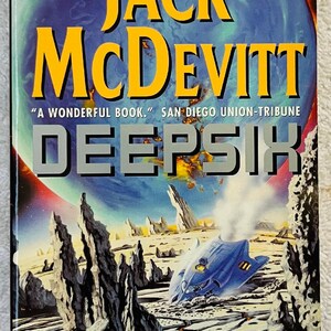 Puede incluir: Portada del libro "DEEPSIX" de Jack McDevitt. La portada presenta un planeta azul con el nombre del autor, "JACK McDEVITT", en amarillo, y el título en plata. También se representa una nave espacial y un paisaje desértico.