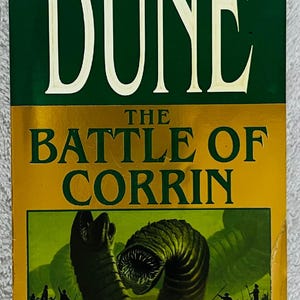 May include: A hardcover book titled "Dune: The Battle of Corrin" by Brian Herbert and Kevin J. Anderson. The cover features a green and gold color scheme with a sandworm illustration and the text "The New York Times Bestseller".