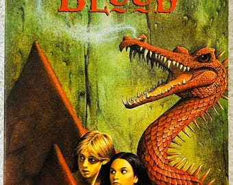 Könnte beinhalten: Buchcover von "Heart's Blood" von Jane Yolen. Es zeigt einen roten Drachen und zwei junge Leute. Der Titel ist in großen, orangefarbenen Buchstaben gehalten. Der Hintergrund ist grün und braun. Veröffentlicht von Magic Carpet Books.