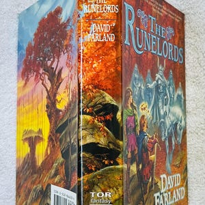 Pode incluir: Um livro de capa dura intitulado "The Runelords" de David Farland. A capa apresenta uma ilustra&ccedil;&atilde;o de fantasia com figuras, um cavalo branco e uma paisagem com uma &aacute;rvore e rochas. A lombada mostra o t&iacute;tulo e o autor.
