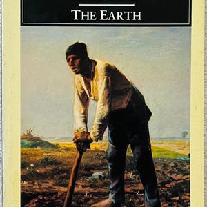 Könnte beinhalten: Ein Penguin Classics Taschenbuch mit dem Titel The Earth von Émile Zola. Das Cover zeigt ein Gemälde einer Person in hellem Hemd und dunkler Hose, die sich auf ein Holzwerkzeug in einem Feld stützt, vor einem blassblauen Himmel und brauner Erde.