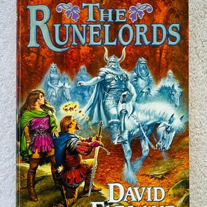 Pode incluir: Capa do livro "The Runelords" de David Farland. A arte da capa retrata uma cena de fantasia com figuras a cavalo, um guerreiro ajoelhado e o t&iacute;tulo em letras grandes e estilizadas. O fundo &eacute; uma mistura de laranja e castanho.