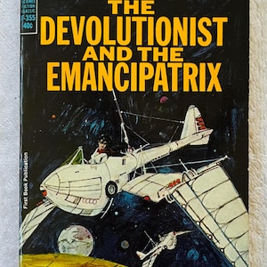 Può includere: Copertina di un libro tascabile vintage per "The Devolutionist and the Emancipatrix" di Homer Eon Flint. La copertina presenta un'astronave bianca con un pilota su uno sfondo spaziale blu scuro. Il testo include "Ace Science Fiction Classic".