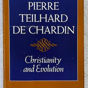 May include: A hardcover book titled "Pierre Teilhard de Chardin" with the subtitle "Christianity and Evolution." The cover features a dark blue rectangle with white text and a gold decorative element, set against a brown background.