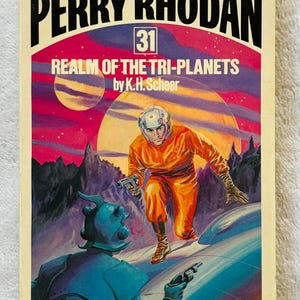 Puede incluir: Portada de libro de bolsillo vintage de "Perry Rhodan 31: Realm of the Tri-Planets" de K.H. Scheer. La portada presenta una escena futurista con una figura con traje naranja sosteniendo una pistola de rayos, sobre un fondo de planetas y un alienígena azul.