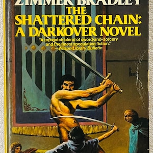 May include: Vintage paperback book cover for "The Shattered Chain: A Darkover Novel" by Marion Zimmer Bradley. The cover art shows a muscular figure with a sword, and other figures. The book's title and author are displayed.