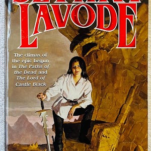 May include: Book cover for "Sethra Lavode" by Steven Brust. The title is in large red letters. The cover features a woman in a white shirt and black pants holding a sword. The book is part of a series.