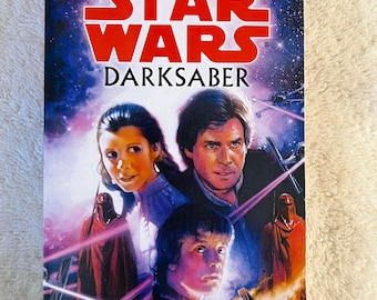 May include: A paperback book titled "Star Wars: Darksaber" by Kevin J. Anderson. The cover features images of characters from the Star Wars universe, with a purple and blue space background. The book is part of the Legends series.