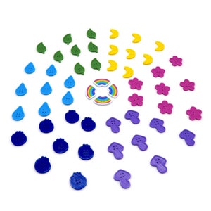 May include: Assortment of colorful buttons in various shapes, including leaves, raindrops, blueberries, mushrooms, and flowers. The buttons are made of plastic and have a smooth, glossy finish.