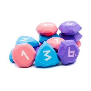 Könnte beinhalten: Eine Gruppe von bunten, geometrischen Würfeln mit den Zahlen 1, 3 und 6. Die Würfel sind aus Kunststoff und haben eine matte Oberfläche.