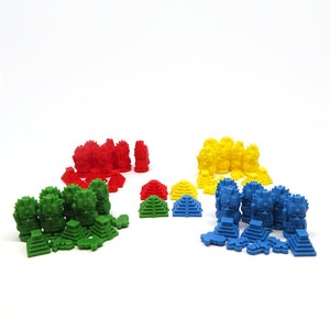 Puede incluir: Un conjunto de piezas de juego de colores, que incluyen figuras y pirámides rojas, amarillas, verdes y azules. Las figuras son estilizadas y tienen un diseño tribal. Las pirámides están apiladas en varios niveles.