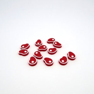 May include: A group of 12 red and white plastic game pieces shaped like a steak.