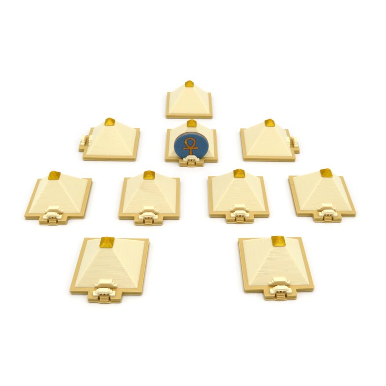 May include: Nine small, beige pyramids with gold tops arranged in a circle around a blue and gold pyramid with an ankh symbol.