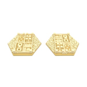 May include: Two beige hexagonal game pieces with a raised design of a city with buildings and a central park. The pieces are made of plastic and have a smooth finish.