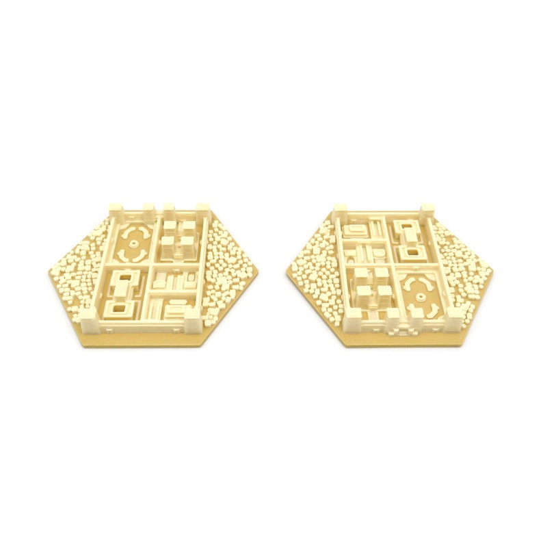 May include: Two beige hexagonal game pieces with a raised design of a city with buildings and a central park. The pieces are made of plastic and have a smooth finish.