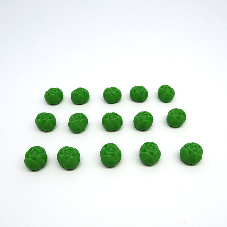 May include: A collection of 15 green miniature plastic brussels sprouts. The sprouts are arranged in three rows of five.