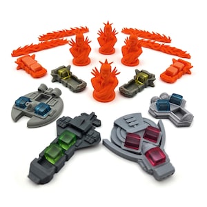 May include: A collection of miniature game pieces including three orange humanoid busts, four orange flame-shaped tokens, two orange rectangular vehicles, and several gray plastic starships featuring translucent blue, green, and red square inserts.