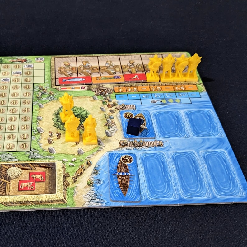 May include: A board game with a wooden board, yellow plastic pieces, and a blue and white water section. The board has a grid with numbers and letters. There are also small wooden pieces on the board. The game is called "The Voyages of Marco Polo".