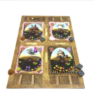 May include: A game board with four colorful spinning wheels, each with a different monster character. The board is made of cardboard and has a brown and tan color scheme. The numbers 1, 0, and 3 are visible on the wheels.