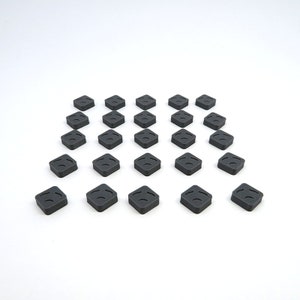 May include: A set of 20 black square-shaped tiles with a raised design. The tiles are arranged in a diamond pattern on a white surface.