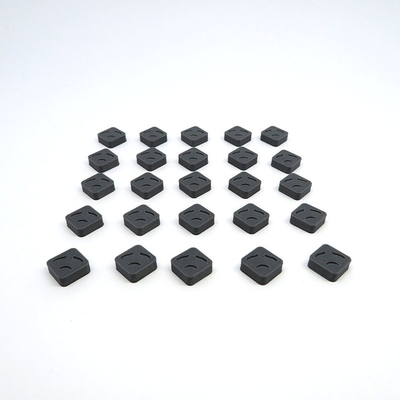 May include: A set of 20 black square-shaped tiles with a raised design. The tiles are arranged in a diamond pattern on a white surface.