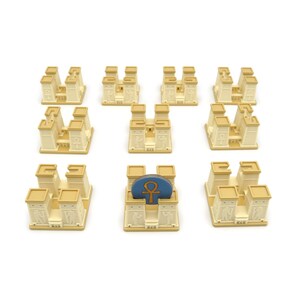 May include: Nine beige temple-shaped game pieces with a blue and gold game piece on top of one of the temples.