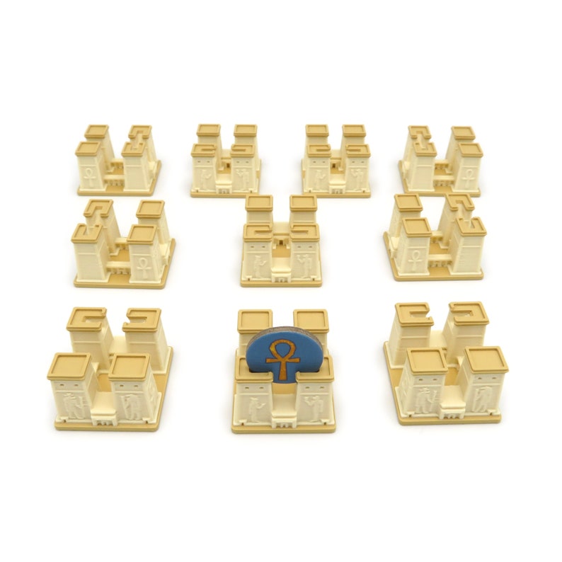 May include: Nine beige temple-shaped game pieces with a blue and gold game piece on top of one of the temples.