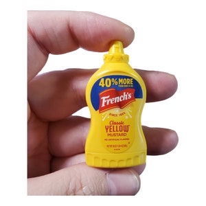 May include: A yellow plastic squeeze bottle of French's Classic Yellow Mustard. The bottle has a yellow cap and a label with the text "40% More Than Our 14 oz." and "French's Since 1904 Classic Yellow Mustard No Artificial Flavors Net Wt 20 oz (1.18 kg)"