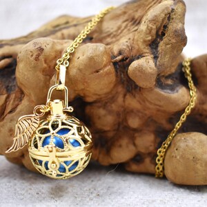 May include: A gold chain necklace with a blue and gold cage pendant. The cage has a small angel wing charm attached to it.