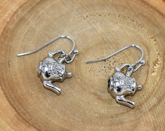 May include: A pair of silver teapot earrings. The earrings are made of metal and have a detailed design.