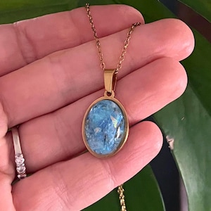 Pingente de resina com pedra cristal azul-claro iridescente e brilhante, em tons de água-marinha e mica, para atrair energia positiva.